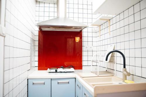 - une cuisine avec un évier et un mur rouge dans l'établissement Studio avec Mezzanine, à Saint-Maur-des-Fossés