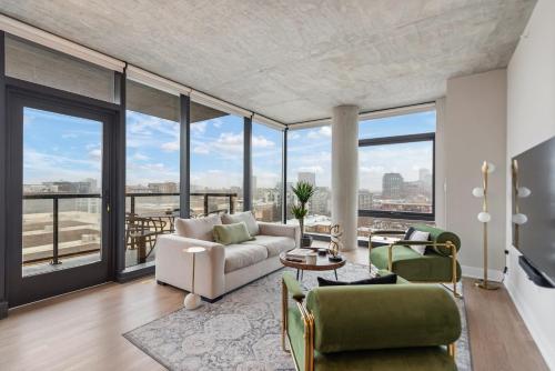 a living room with a couch and chairs and windows at Sage Modern Apartments Near Union Park in West Loop in Chicago