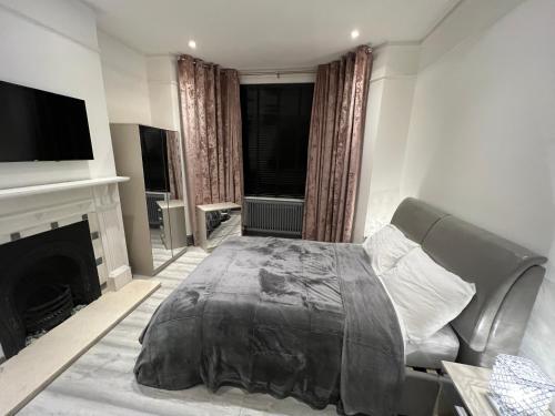 a bedroom with a bed and a tv and a fireplace at UrbanNess Stays - Rooms with Stylish Comfort in the Heart of Croydon in Croydon
