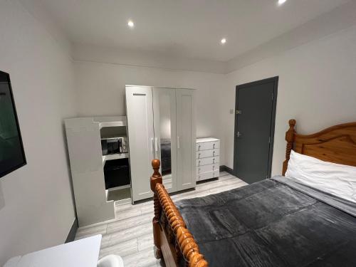 a bedroom with a large bed and a kitchen at UrbanNess Stays - Rooms with Stylish Comfort in the Heart of Croydon in Croydon