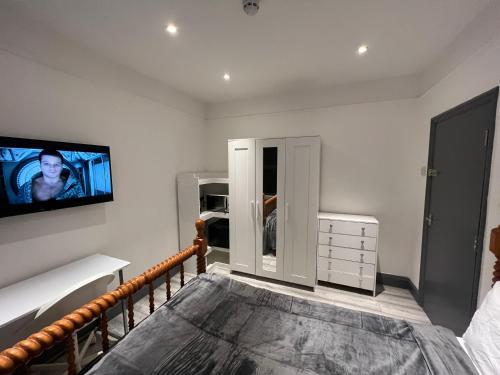 a bedroom with a bed and a tv on the wall at UrbanNess Stays - Rooms with Stylish Comfort in the Heart of Croydon in Croydon