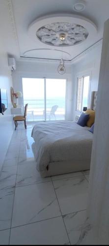 a white bedroom with a bed and a large window at Blue ocean villa in Asilah