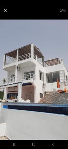 a large white house with a swimming pool in front of it at Blue ocean villa in Asilah