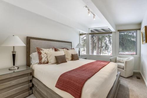 a bedroom with a large bed and a chair at Deluxe Condo with Big Windows Downtown Aspen in Aspen