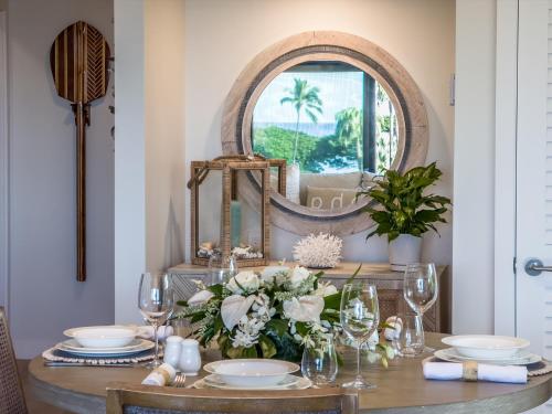 a dining room table with a mirror and flowers at Panoramic Ocean Views! Remodeledredecorated! Very Pretty Corner Ground Floor 2 Bedroom2 Bath in Wailea
