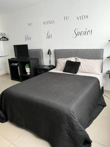 a bedroom with a bed with a black comforter at Lindo y comodo Loft in Hércules