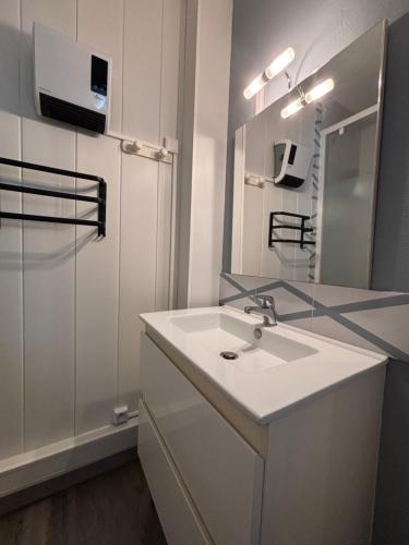 une salle de bain blanche avec un lavabo et un miroir dans l'établissement Résidence Aigue Marine Front de Mer, au Cap d'Agde