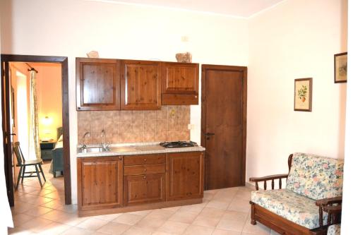 a kitchen with wooden cabinets and a sink and a chair at Agriturismo Fara del Falco in Vieste