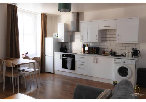 a kitchen with white cabinets and a table and a table and a tableablish at Stay Central - 2BR Apartment Near Beach & City Highlights in Minehead
