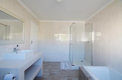 a white bathroom with a shower and a sink at Tassies in Gansbaai