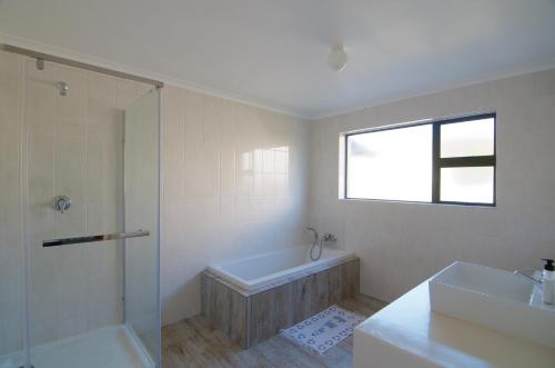 a bathroom with a tub and a shower and a sink at Tassies in Gansbaai