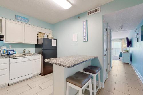 a kitchen with white cabinets and a black refrigerator at Islander W 703 in Fort Walton Beach