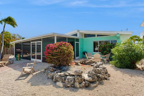 a house with chairs and a fire pit in front of it at Downhome Cabin by the Canal in Key Colony Beach