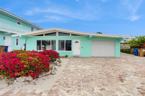 a blue house with flowers in front of it at Downhome Cabin by the Canal in Key Colony Beach
