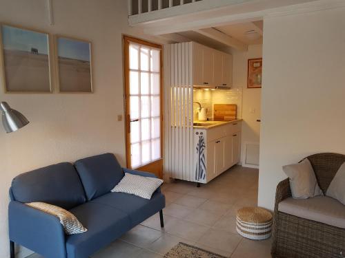 un salon avec un canapé bleu et une cuisine dans l'établissement Gruissan Ayguades maison de vacances L'Etang 4 personnes, à Gruissan