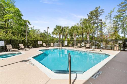 a swimming pool with chairs and a fence at Best Western PLUS Westgate Inn and Suites in Leland
