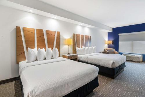 a hotel room with two beds and a chair at Best Western PLUS Westgate Inn and Suites in Leland