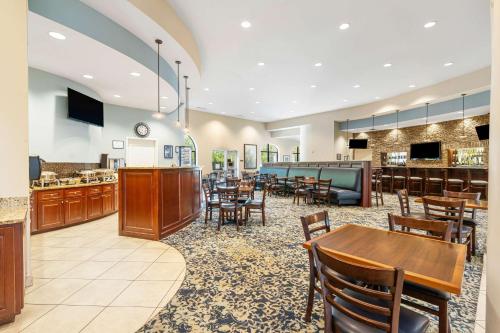 Un restaurante con mesas y sillas y un bar. en Best Western PLUS Westgate Inn and Suites, en Leland