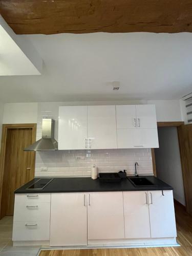 a kitchen with white cabinets and a sink at Dolce apartman Zlatibor in Zlatibor