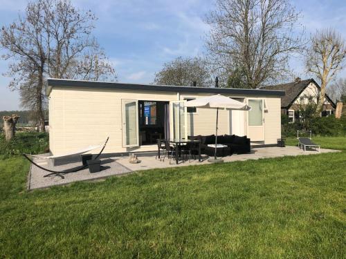 ein kleines Haus mit einer Terrasse und einem Sonnenschirm in der Unterkunft Landelijk gelegen chalet aan de Vecht vlakbij Amsterdam in Nigtevecht