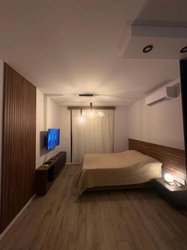 Un dormitorio con una cama y un televisor de pantalla plana. en Mendoza, en Rosario