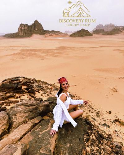 a woman sitting on a rock in the desert at Ayla Rum Luxury Camp in Wadi Rum