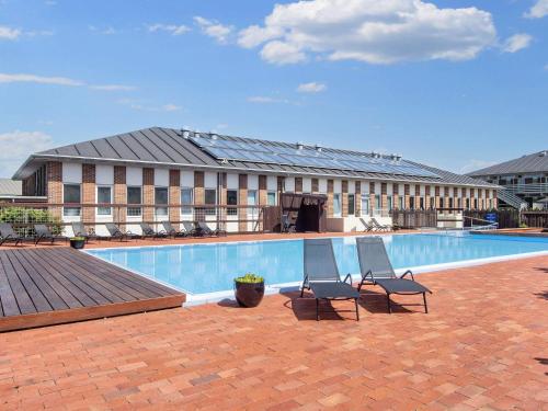 a hotel with a swimming pool with two chairs and a building at Apartment Fanø VII in Fanø