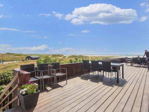 a wooden deck with tables and chairs on the beach at 6 person holiday home on a holiday park in Fanø in Fanø
