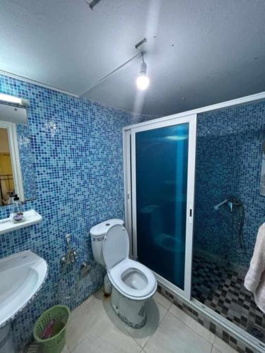 a blue tiled bathroom with a toilet and a tub at Maison fatha in Kelibia