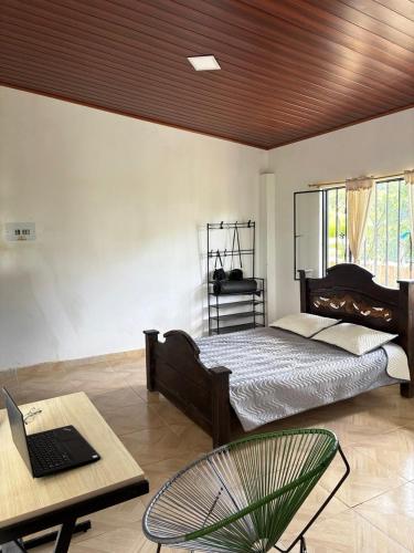 1 dormitorio con cama y mesa con ordenador portátil en Casa Jaguar Viotá, en Viotá