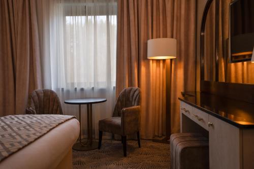 a hotel room with a bed and a table and a window at Crossbasket Castle, Hotel & Restaurant in High Blantyre