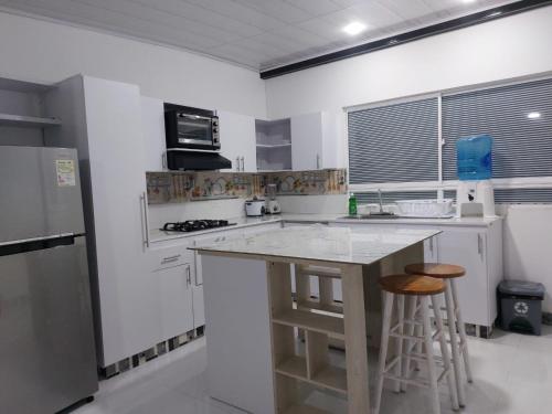 a white kitchen with a counter and two bar stools at Posada Cocos Place in San Andrés