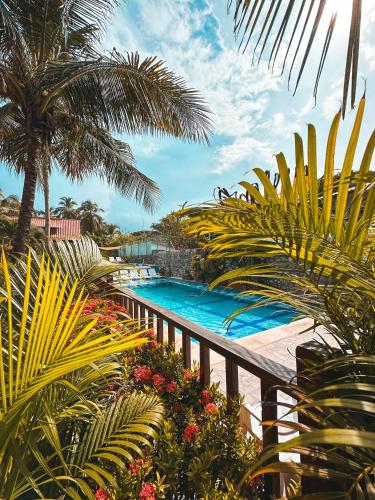 a swimming pool in a resort with palm trees and plants at Praba Hostel in Palomino