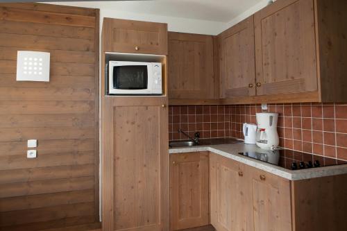 a kitchen with wooden cabinets and a microwave at Village vacances de Valmeinier "Les Angeliers" in Valmeinier