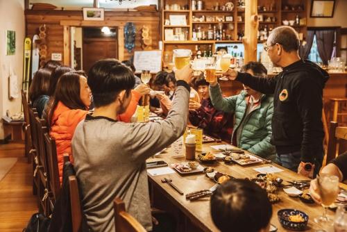 a group of people sitting at a table drinking beer at Lodge Jotenki in Kiso