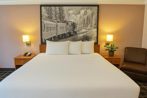 a hotel room with a bed and a train painting on the wall at Creekside Inn & Suites in Willits