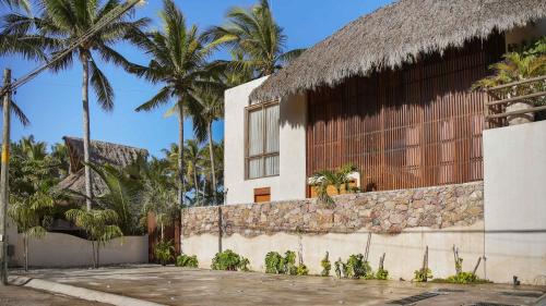 a house with a stone wall and palm trees at Beachfront Villa Punta Mita Litibu in Higuera Blanca