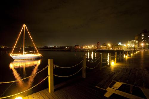 a sailboat with lights on the water at night at Business Hotel KG in Oita