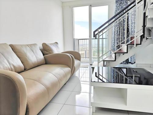 a living room with a couch and a staircase at Cozy 1BR Casa De Parco Apt with Pool & Gym in Samporo