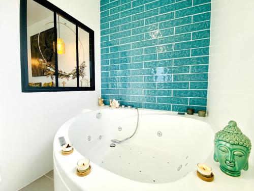a bath tub in a bathroom with a blue brick wall at Villa chic & Zen - Workation - Plage à 10min in Vaux-sur-Mer