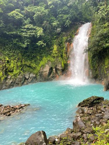 a waterfall in a river with blue water at Kakao Lodge & Garden Río Celeste in Bijagua
