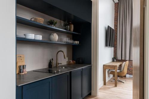 a kitchen with black cabinets and a sink and a table at The Skowhegan By Kasa in Skowhegan