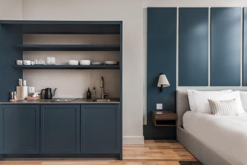 a bedroom with blue walls and a bed and a kitchen at The Skowhegan By Kasa in Skowhegan