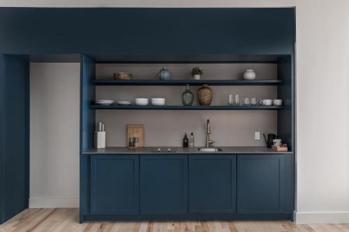 a blue kitchen with a sink and shelves at The Skowhegan By Kasa in Skowhegan
