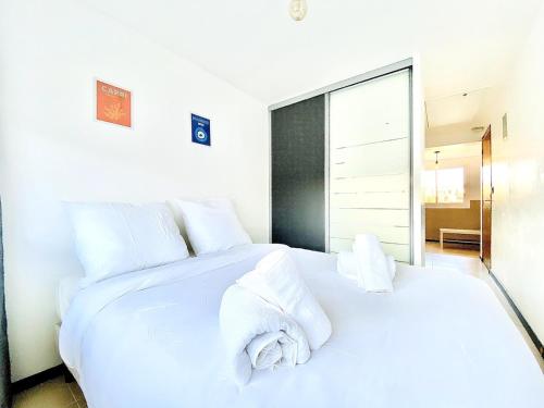 une chambre avec un lit blanc avec des serviettes dessus dans l'établissement À 1 voie piétonne de la plage, du centre et du port pour 1 à 4 personnes, à La Ciotat