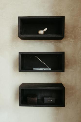 Dos estantes negros con un reloj en la pared. en The Iggy Hotel Seseh Loft 8, en Cemagi
