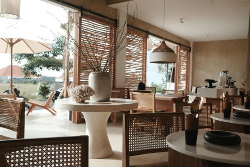 a dining room with tables and chairs and windows at The Iggy Hotel Seseh Loft 8 in Cemagi