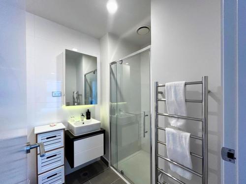 a white bathroom with a sink and a shower at Beautiful Apartment w sea view in Auckland
