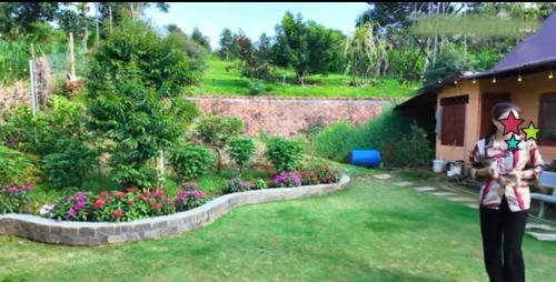 a woman standing in a yard with a garden at Cozy Hill Retreat in Gia Nghĩa