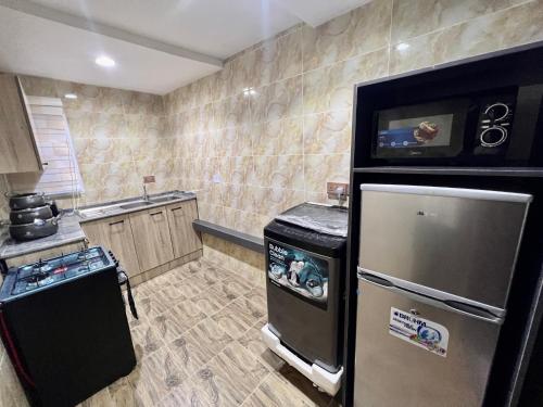 a kitchen with a refrigerator and a tv on the wall at Konar-Apts, 1 bedroom shortlet with City view Balcony, 24hrs power, Security, Wifi, Gwarinpa Express by Dawaki Junction in Kubwa